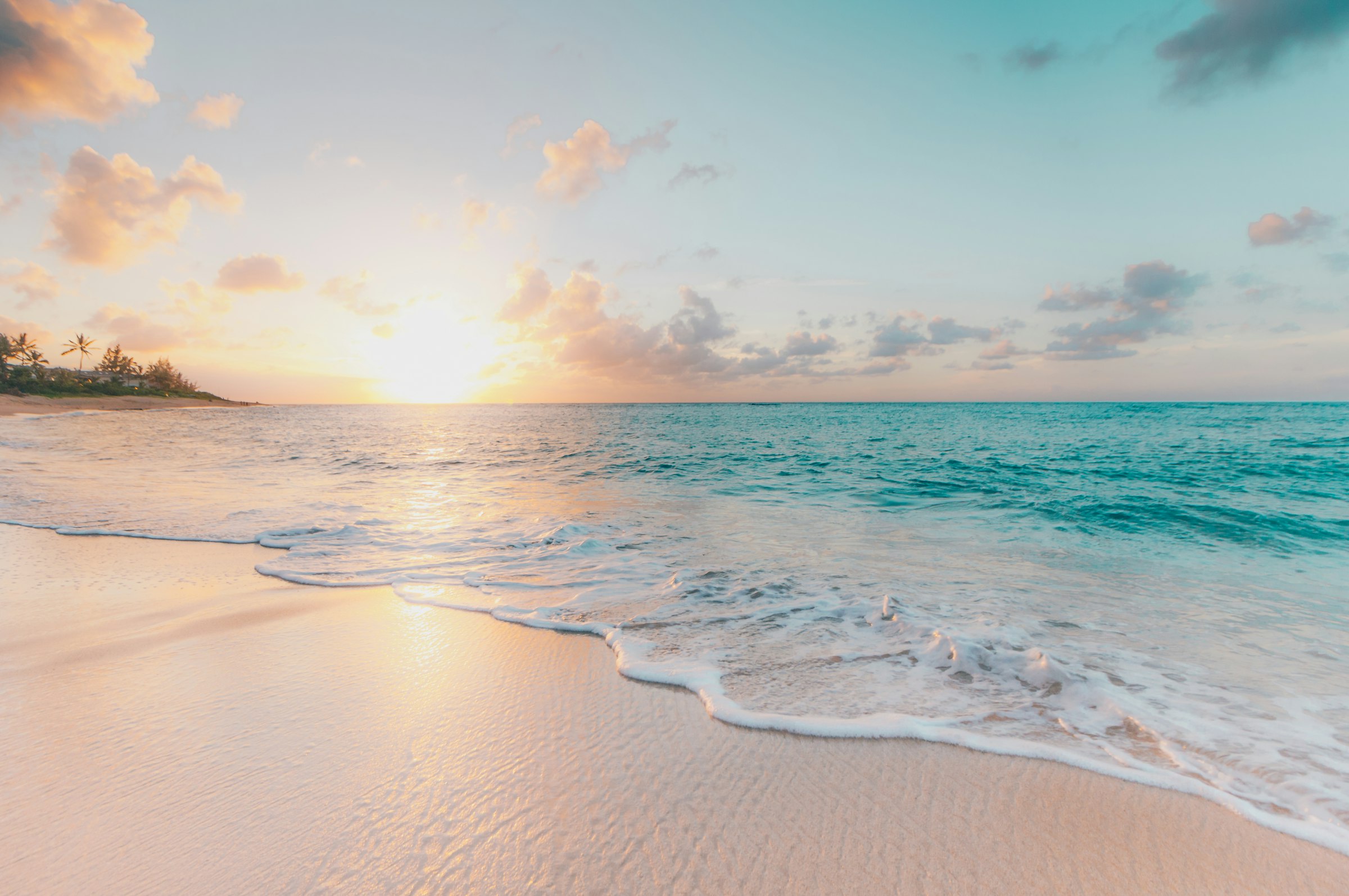 Gentle waves washing onto a sandy beach at golden-hour sunset