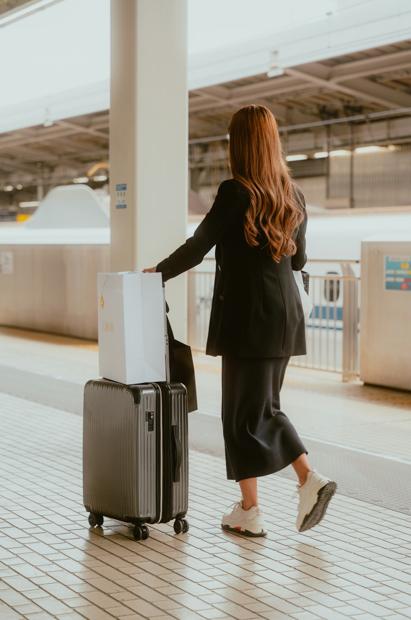 A woman with luggage waiting on a train station platform